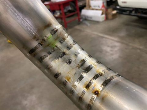 1996 Ford Bronco - A close-up shot shows a metal pipe with numerous welds, some showing discoloration and residue.
