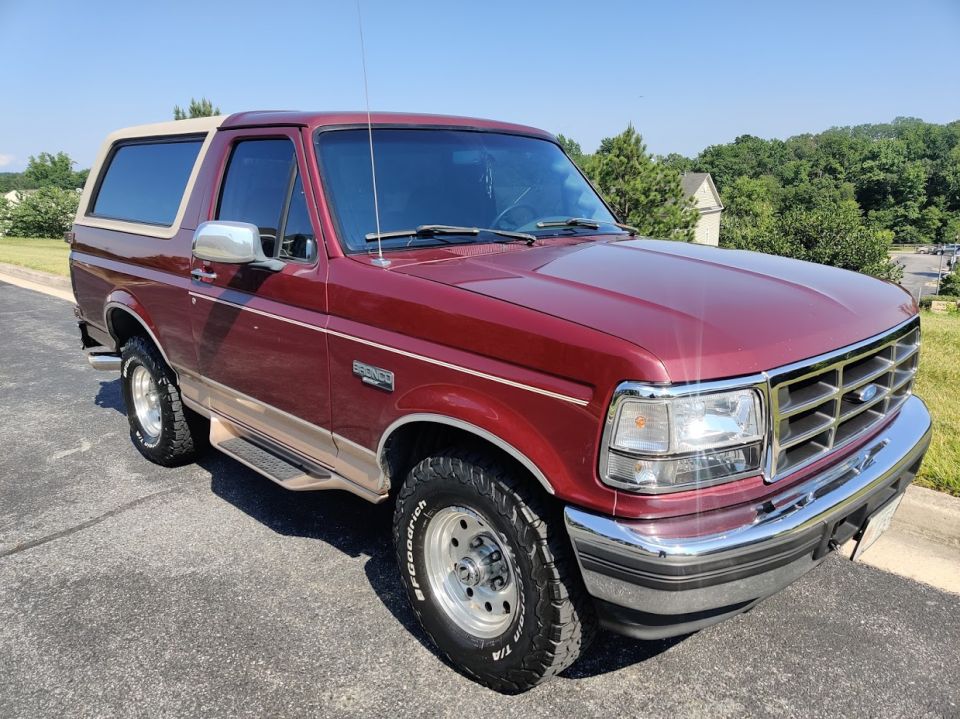 Maroon Ford Bronco with tan top, parked on asphalt driveway
