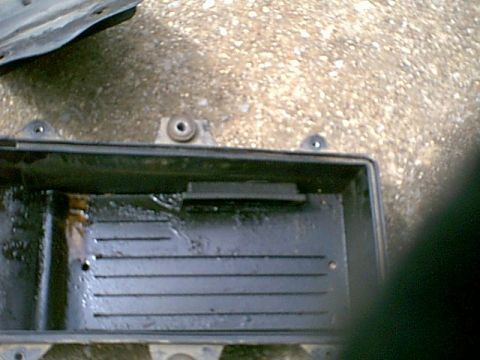 1988 Ford Bronco - Close-up of an engine oil pan, showing internal ribbed structure and oil residue.