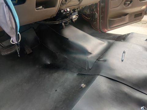 1996 Ford Bronco - The interior floor of a vehicle shows black rubber matting installed over the original flooring.