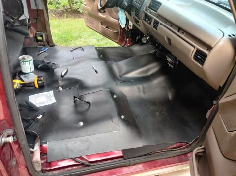 1996 Ford Bronco - The interior of a vehicle is being worked on, with sound deadening material being installed on the floor.