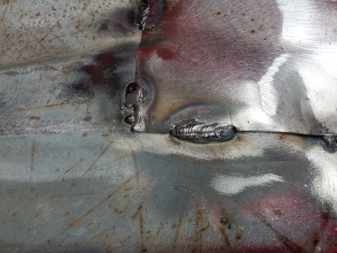 1994 Ford Bronco - This image shows a close-up view of a metal panel with multiple weld seams and beads, indicating repair or fabrication work.