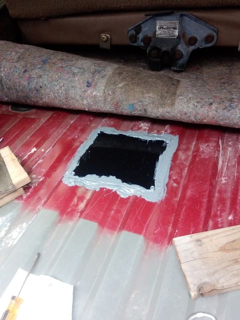 1994 Ford Bronco - A patch is being installed on the vehicle's floor, covering a section with sealant.
