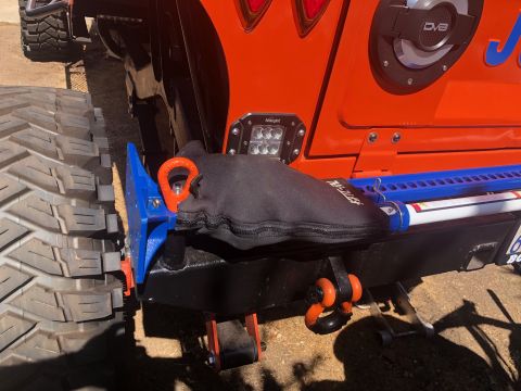 1992 Jeep Wrangler - A close-up rear view of an orange Jeep Wrangler shows a black fabric cover over a blue tow hitch mounting bracket with an orange tow ring.…