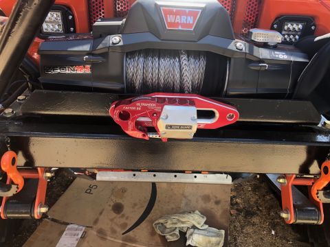 1992 Jeep Wrangler - A close-up view of an orange Jeep Wrangler's front end, featuring a WARN Zeon 12S winch mounted on a black bumper. A red and silver "UltraH…