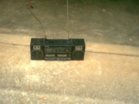 1988 Ford Bronco - A black boombox sits on a concrete surface, its antenna extended.