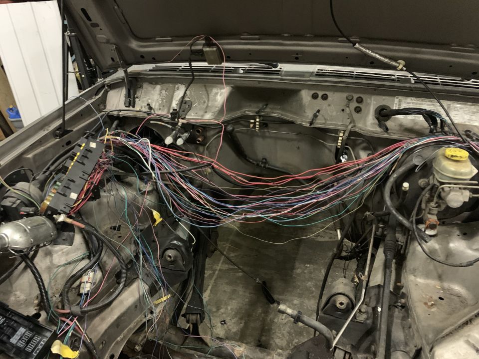 Jeep Cherokee engine bay with open hood, showing a large, complex wiring harness and fuse boxes.
