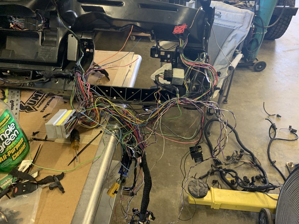 Disassembled dashboard wiring harness with many colorful wires.