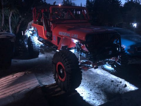 1992 Jeep Wrangler - An orange Jeep Wrangler, nicknamed "General Lee" with the number "01" on the side, is parked outdoors at night with bright lights illuminat…