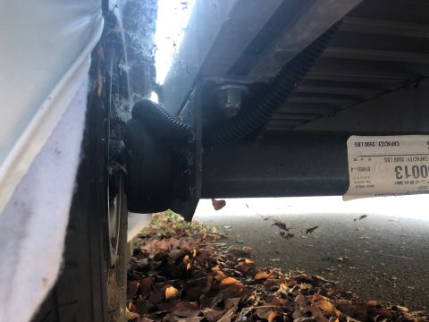 1992 Jeep Wrangler - A close-up, low-angle view shows the underside of a trailer frame with a tire and a black bellows boot visible on the left. A label on the…