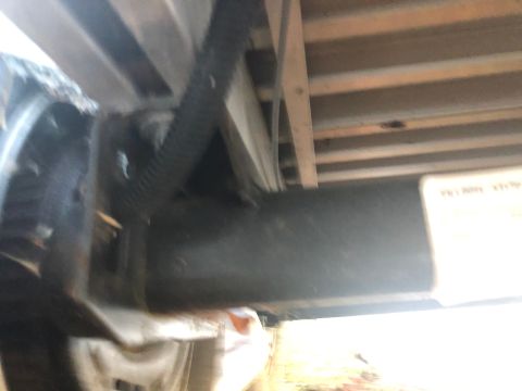 1992 Jeep Wrangler - Underside view of a black trailer hitch assembly attached to a vehicle frame, with a corrugated hose running above it. A white label with t…