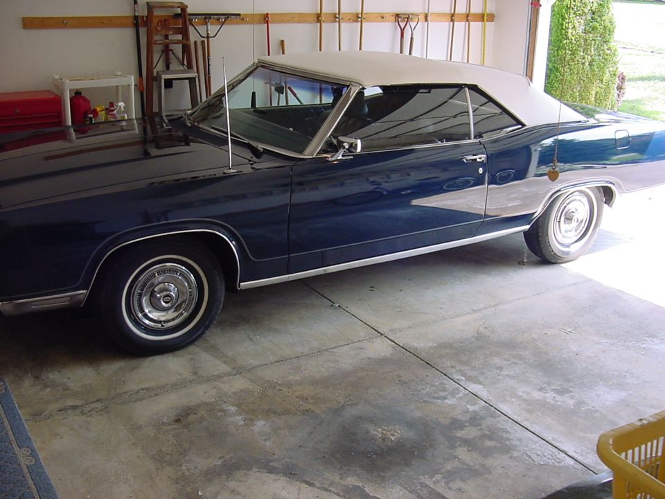 1967 Ford Galaxie convertible, dark blue with a tan top, parked in a garage