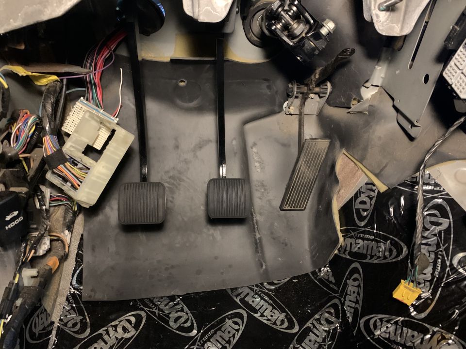 Jeep Cherokee interior footwell with pedals, wiring, and sound deadening.