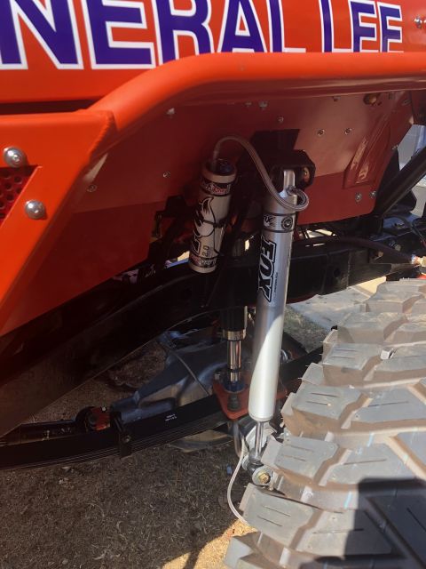 1992 Jeep Wrangler - A close-up view of the suspension system of an orange Jeep Wrangler, featuring two Fox shock absorbers and leaf springs. The text "GENERAL…