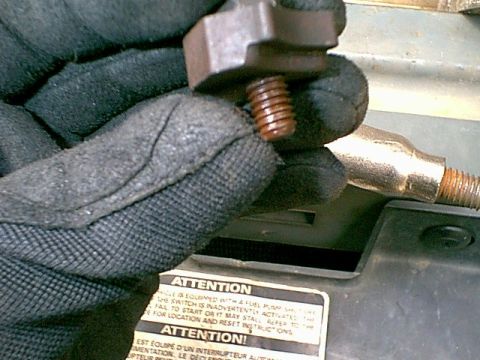 1988 Ford Bronco - A gloved hand manipulates a rusty bolt, with an "Attention" sticker visible on the vehicle's surface.