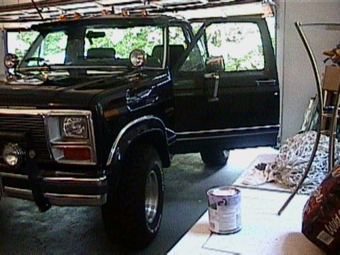 1986 Ford F-150 - This black crew cab pickup truck is shown from a 3/4 front angle with its doors open.