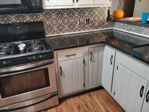 1980 Yugo Vega - A kitchen scene with a stove, cabinets, and patterned backsplash.