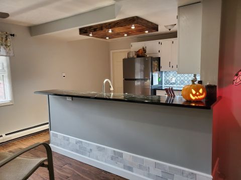 1980 Yugo Vega - A kitchen scene a granite-topped island with a sink, a refrigerator, and a carved pumpkin for Halloween.