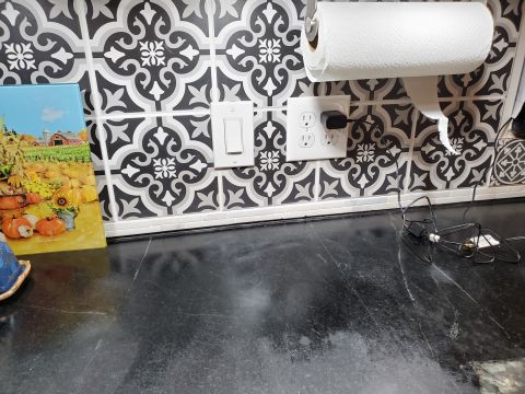 1980 Yugo Vega - A kitchen counter features a decorative tile backsplash, a paper towel dispenser, and electrical outlets.