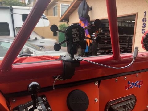1992 Jeep Wrangler - Interior view of a red Jeep Wrangler showing a RAM Mounts X-Grip phone holder attached to a roll bar, a gear shifter, and a "Jeep" decal on…