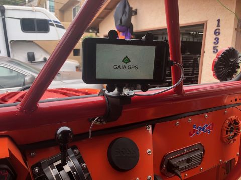 1992 Jeep Wrangler - The interior of a red Jeep Wrangler features a smartphone mounted on a flexible arm displaying the Gaia GPS app. A black gear shifter and o…