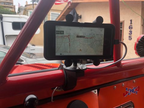 1992 Jeep Wrangler - A close-up interior view of a red Jeep Wrangler shows a smartphone mounted on the roll cage, displaying a GPS map. The vehicle's dashboard…