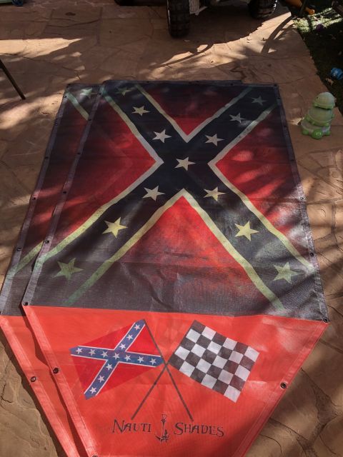 1992 Jeep Wrangler - A large mesh banner with a Confederate flag design is laid out on a stone patio. The lower portion of the banner features a smaller Confede…