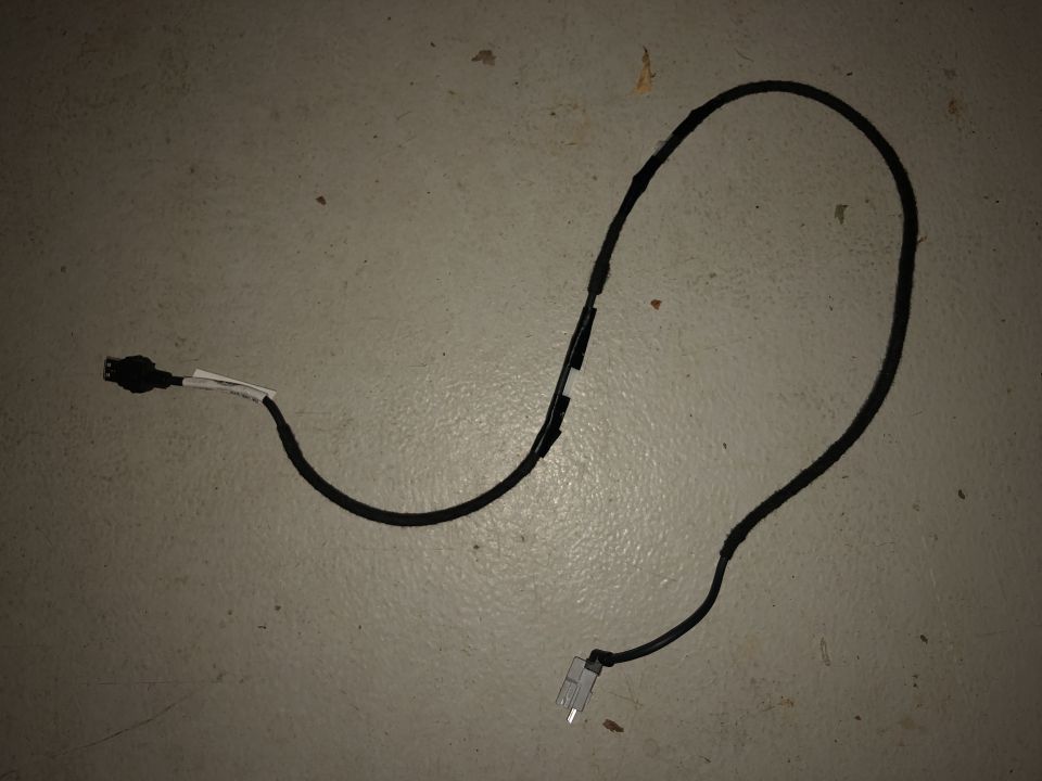 Black loomed cable with white label and connectors on both ends, coiled on a light floor