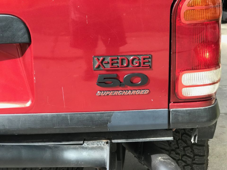 Rear of a red Ford Explorer with X-EDGE 5.0 SUPERCHARGED badge