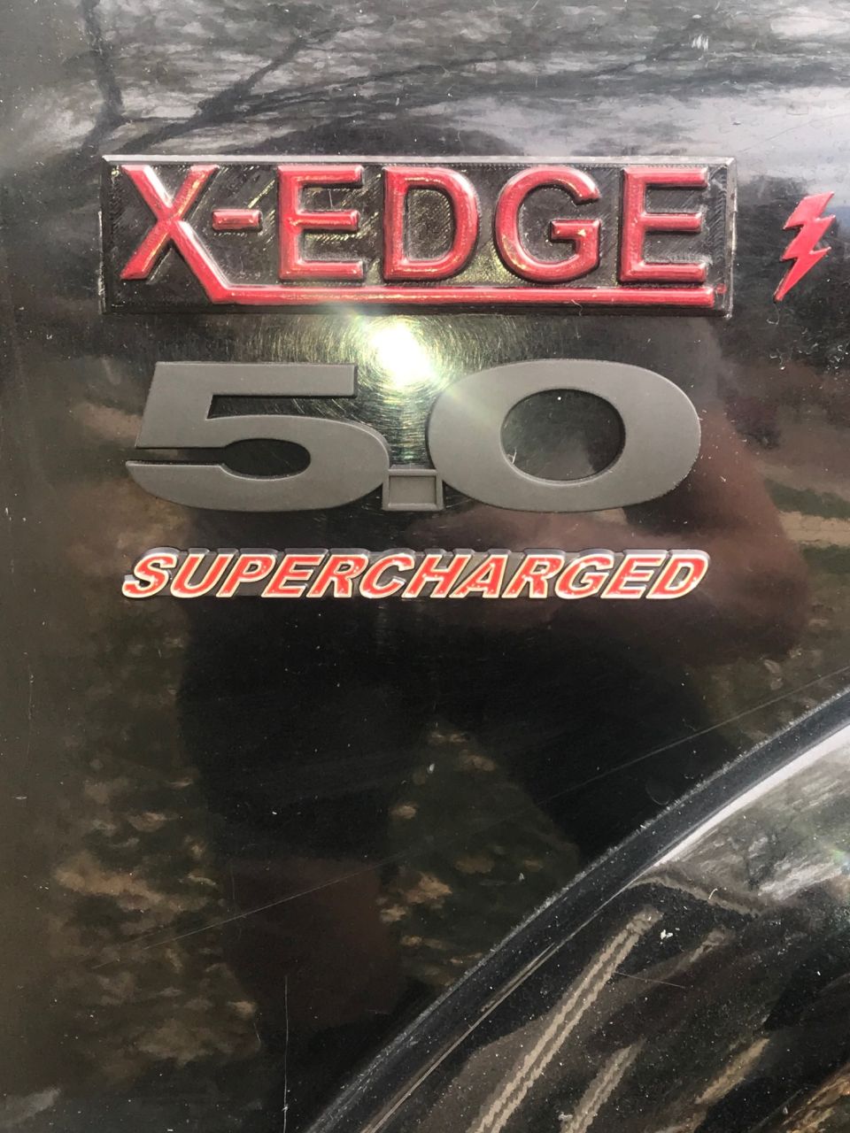 X-EDGE 5.0 SUPERCHARGED badge on a black vehicle.