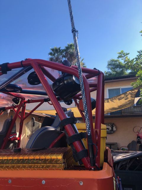 1992 Jeep Wrangler - A close-up view of the roll cage and seating area of a custom off-road vehicle, featuring a red roll cage, black seats, and a diamond plate…
