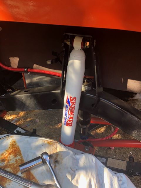 1992 Jeep Wrangler - A white shock absorber with red and blue "SKYJACKER HYDRO 7000" branding is mounted to the black frame of a vehicle. Tools are visible on a…
