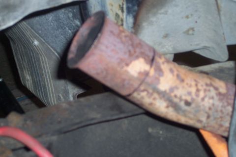 1978 Ford Bronco - A close-up, angled view of a rusty, weathered exhaust pipe, likely from a vehicle's undercarriage. The pipe shows signs of wear and tear, w…