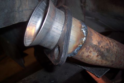 1978 Ford Bronco - A close-up view shows a newly welded exhaust pipe flange attached to a rusty exhaust pipe. The flange has a flared opening with visible mac…