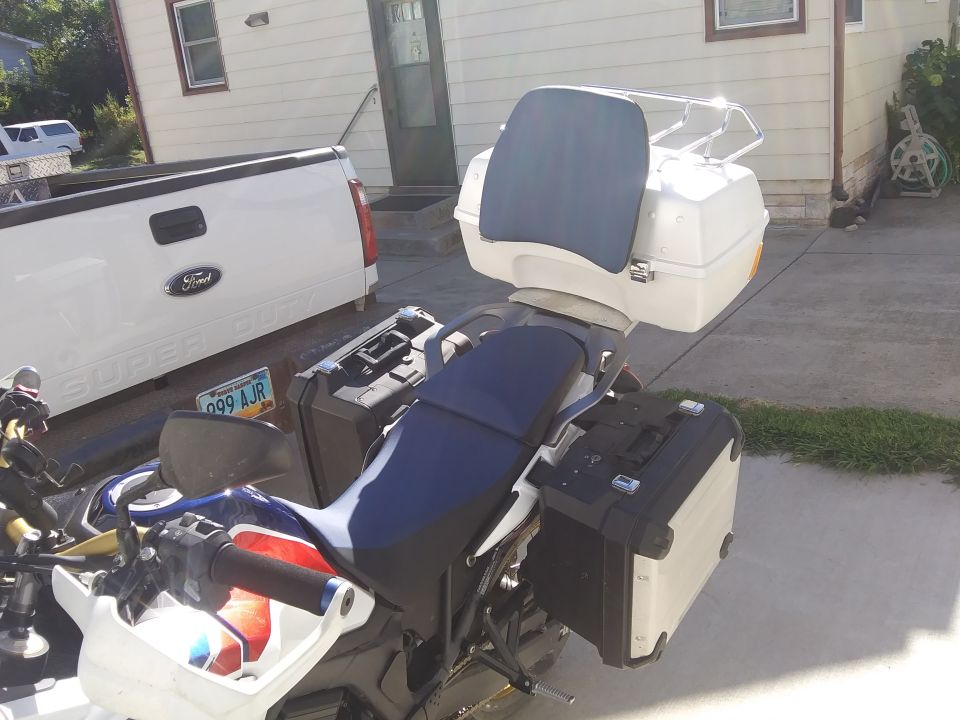 Motorcycle with saddlebags and top case parked next to a white Ford Super Duty pickup truck.