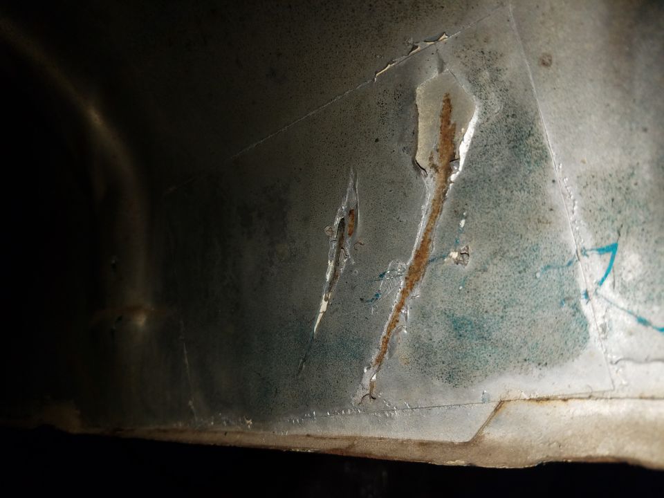 Interior panel with peeling paint, rust streaks, and scratches. Teal undercoat visible