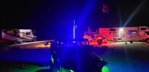 1992 Jeep Wrangler - An off-road vehicle is illuminated by blue and green lights at a campsite with RVs in the background.