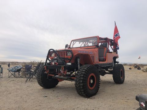 1992 Jeep Wrangler - This heavily modified Jeep Wrangler is parked in a desert landscape with chairs set up nearby.