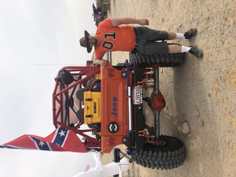 1992 Jeep Wrangler - A man poses with a heavily modified Jeep buggy, a roll cage and large off-road tires.