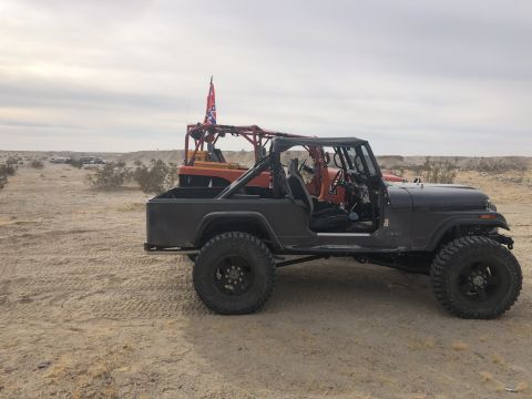 1992 Jeep Wrangler - A modified Jeep CJ-7 sits in a desert landscape next to another off-road vehicle flying a Confederate flag.