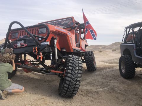 1992 Jeep Wrangler - Modified 1992 Jeep Wrangler parked in a desert landscape with another Jeep nearby. A Confederate flag is mounted on the rear.