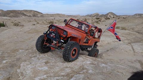 1992 Jeep Wrangler - Modified Jeep CJ-7, likely from the 1970s, navigates a desert landscape with a Confederate flag attached.