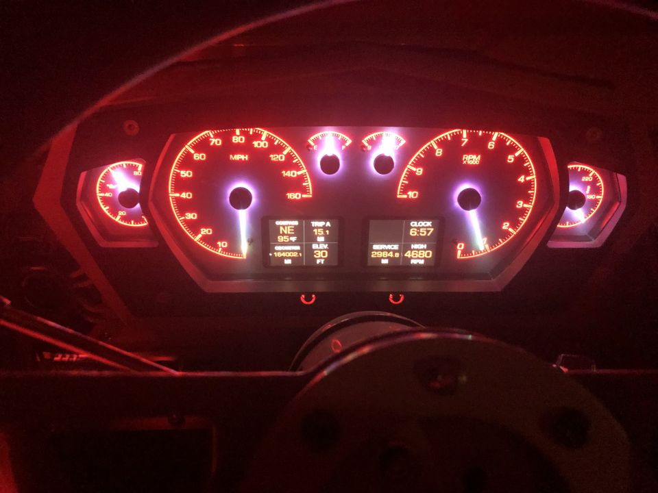 Vehicle dashboard with glowing red gauges, digital displays showing clock, trip, and engine data