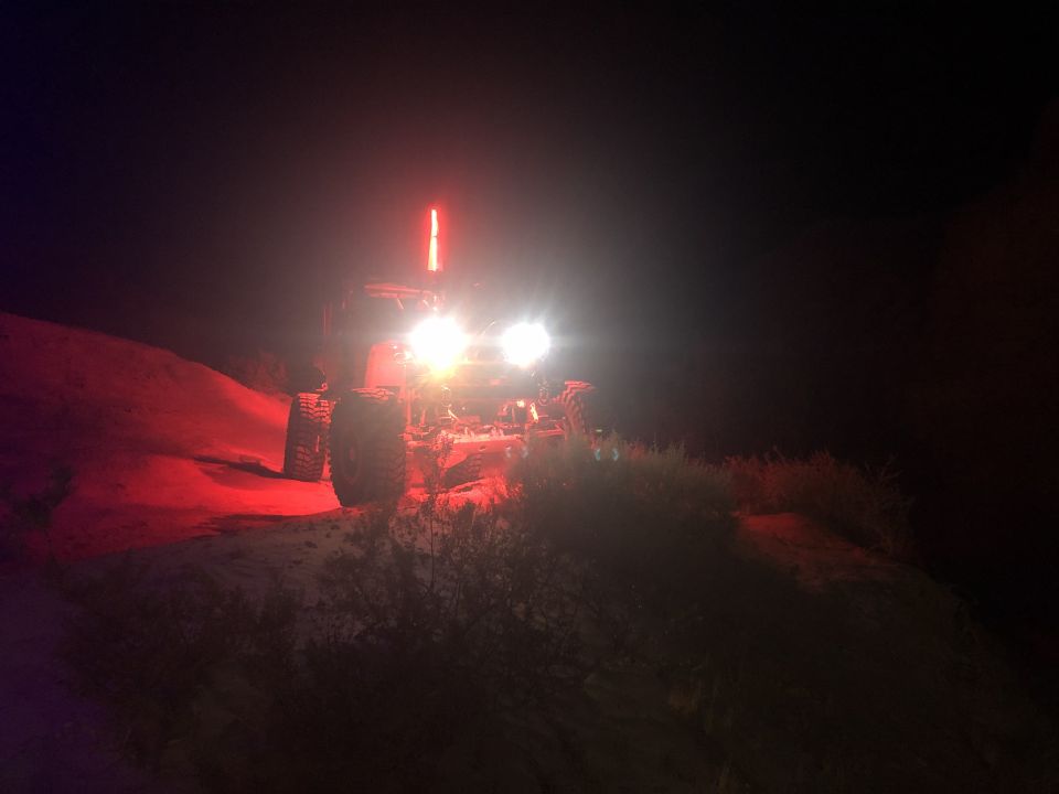 Off-road vehicle with bright headlights and a red light bar at night