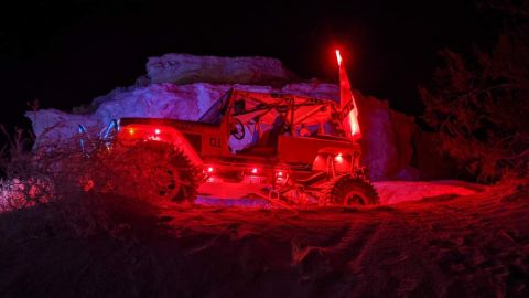 1992 Jeep Wrangler - This modified buggy is illuminated with red and blue lights during a nighttime off-road excursion.