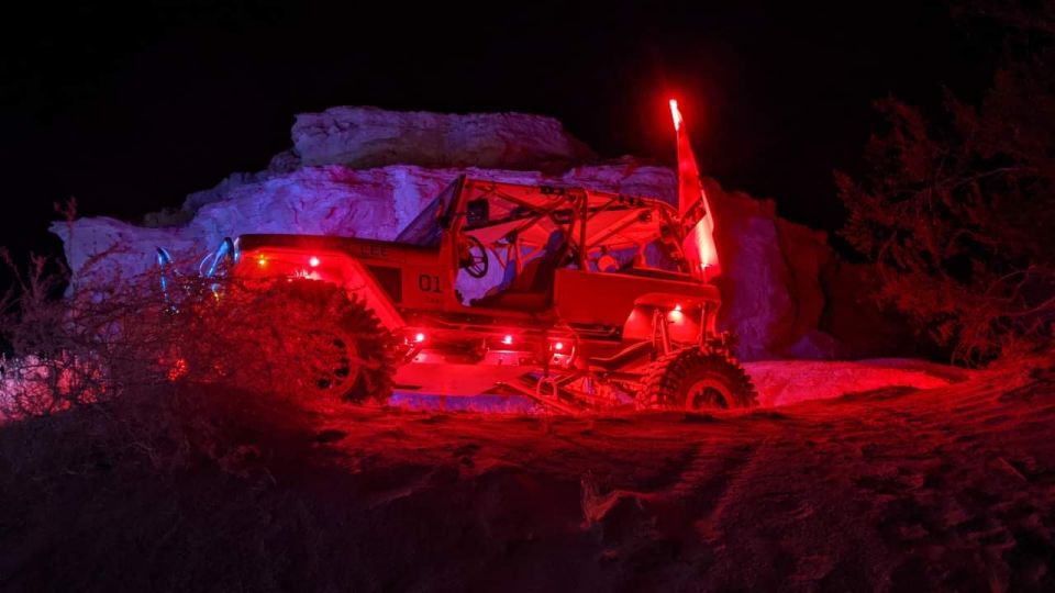 off-road buggy with red and blue lights, and a red flag on top, driving at night