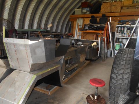 1992 Ford Bronco - Unfinished vehicle bodywork is seen in a workshop, with a large tire in the foreground.