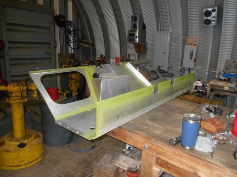1992 Ford Bronco - Unfinished aluminum hull section sits on a wooden workbench in a workshop.