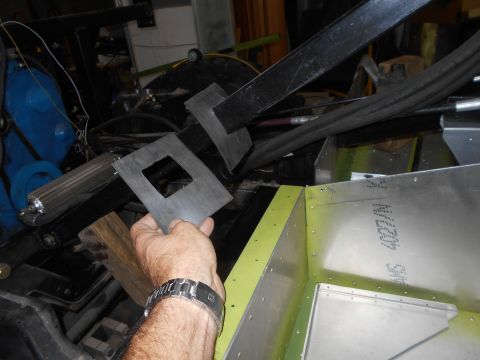 1992 Ford Bronco - A hand holds a metal bracket with a square cutout, positioned above an aluminum structure with visible rivets and text.