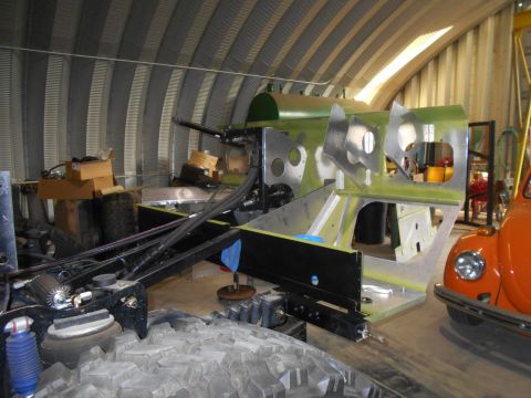 1992 Ford Bronco - A partially assembled vehicle chassis is shown in a workshop, with another classic car visible in the background.